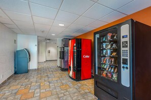 Un couloir avec des distributeurs automatiques, un réfrigérateur et un autre réfrigérateur aux couleurs de Coca-Cola.