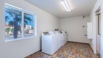 A laundry room with a large window, a washing machine, a dryer, and a water heater.