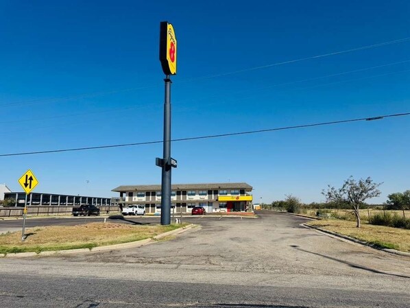 A gas station with a yellow sign, a building in the background, and a clear blue sky.
