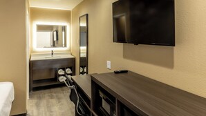 A hotel room with a wooden vanity, a flat-screen TV mounted on the wall, a mirror above the vanity, and a towel rack. - Super 8 by Wyndham Big Spring (Big Spring)