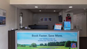 A reception desk with a digital screen displaying a booking message. - Motel 6 Lufkin, TX (Lufkin)