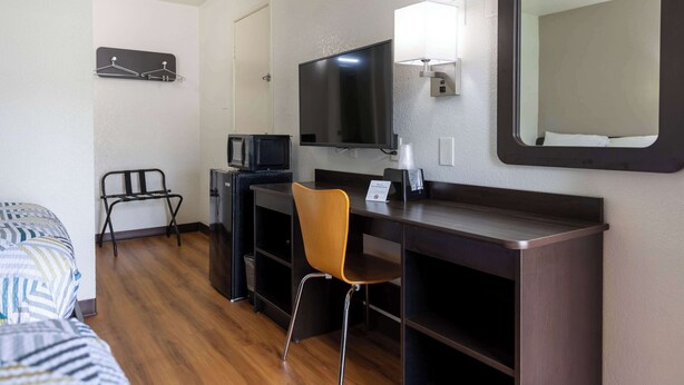A hotel room with a bed, a desk with a chair, a television, and a mirror. - Motel 6 Lufkin, TX (Lufkin)