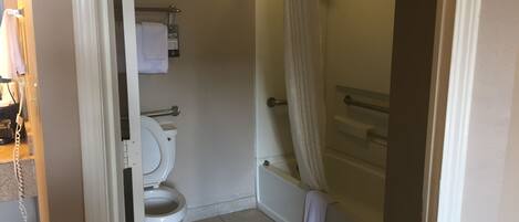A bathroom with a toilet, a shower with a curtain, and a towel rack.