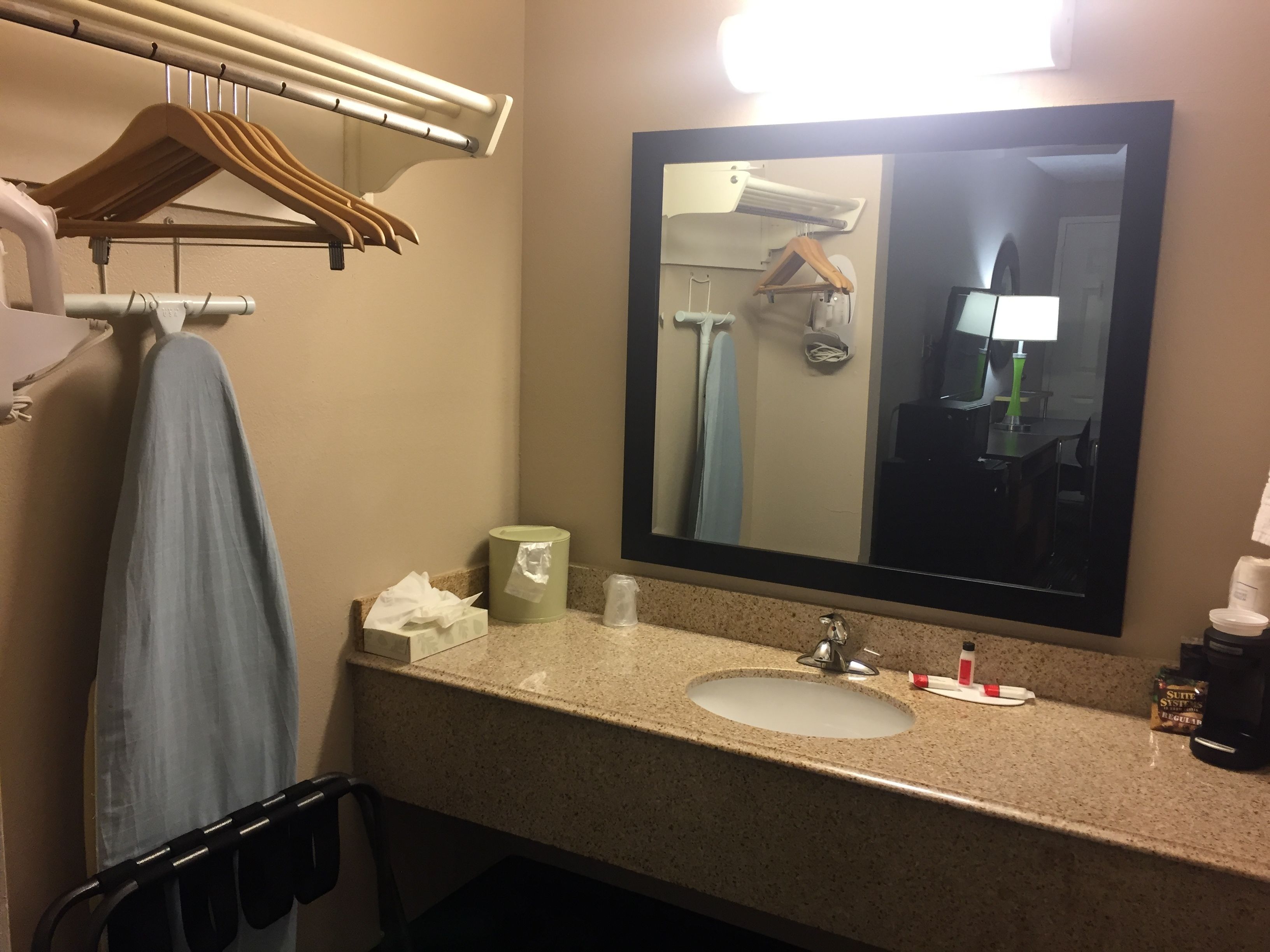 Une salle de bain équipée d’un lavabo, d’un miroir, d’un porte-serviettes et d’une serviette suspendue.