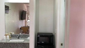 A compact bathroom with a sink, mirror, and a black microwave. - Motel 6 Clute, TX (Clute)