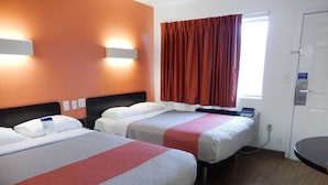 A hotel room with two beds, a window with curtains, a bedside table, and a door. - Motel 6 Clute, TX (Clute)