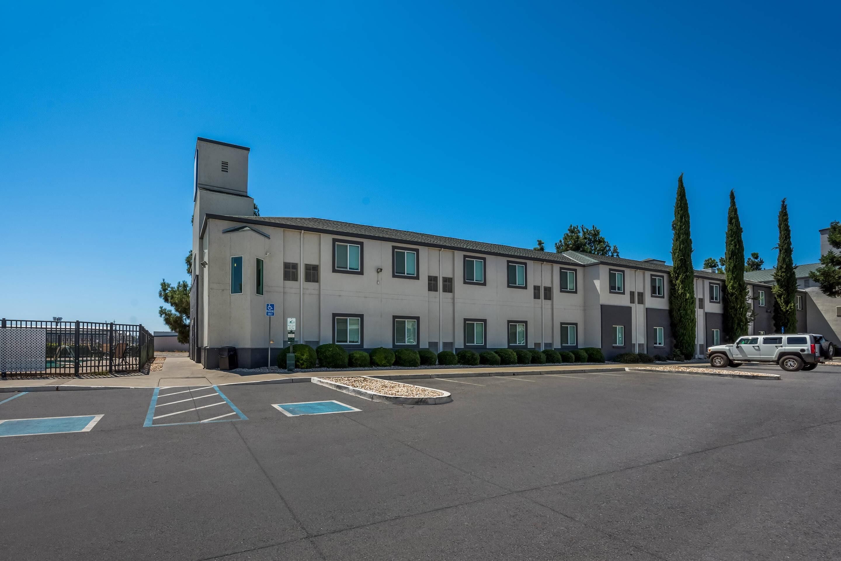 A modern building with a parking lot, a gated entrance, and a vehicle parked inside.
