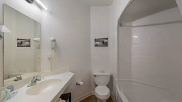A bathroom with a sink, mirror, toilet, and bathtub.