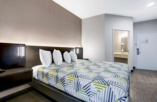 Habitación de hotel con cama, mesitas de noche, televisor de pantalla plana y puerta que da al baño.