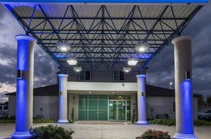 Un edificio con acceso cubierto, amplias columnas y estructura de techo metálica.