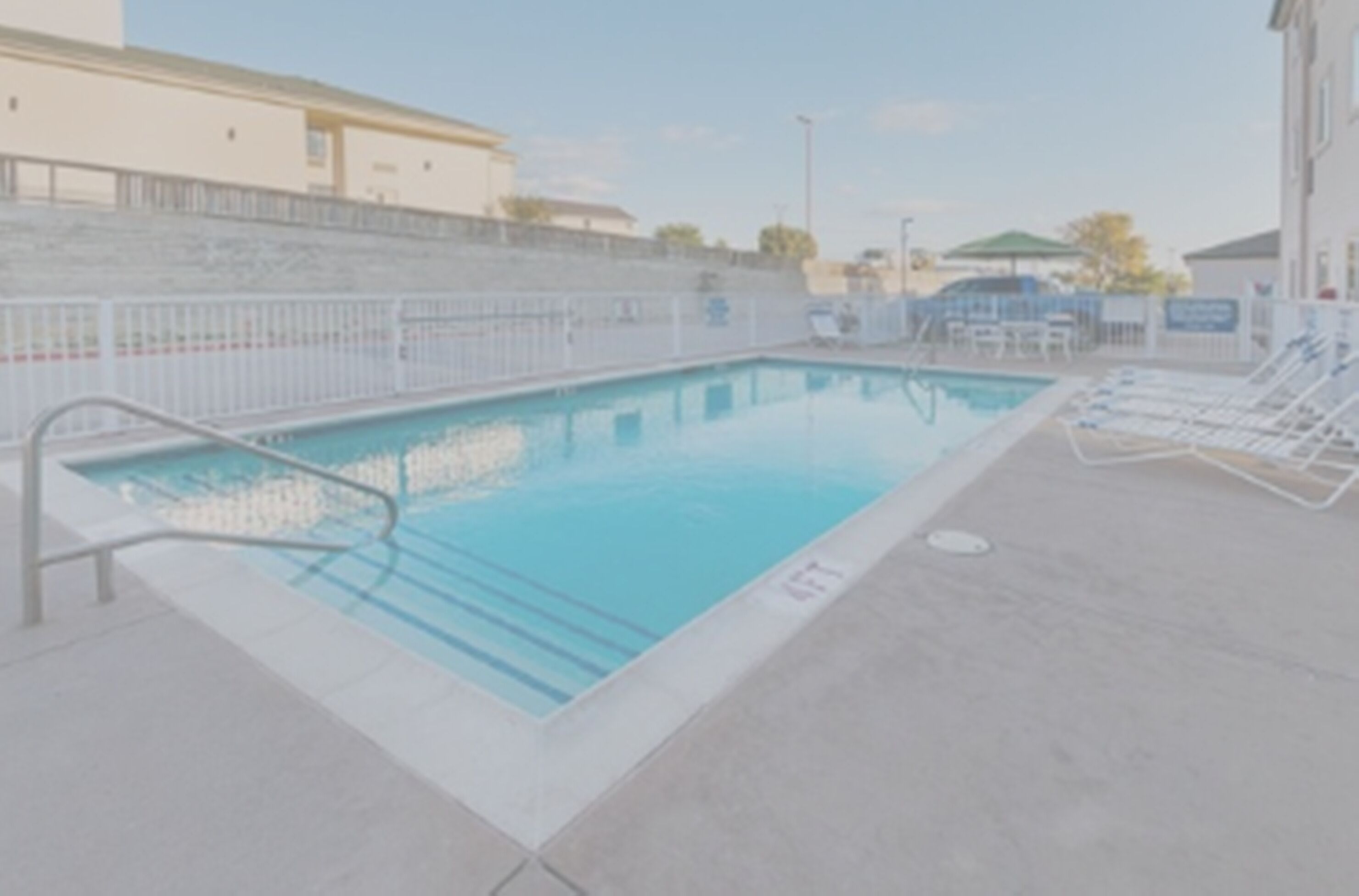 A swimming pool with a tiled deck and lounge chairs.