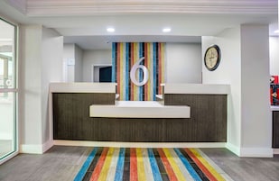 Un área de recepción con un gran número 6 en la pared, un reloj y una alfombra colorida a rayas.