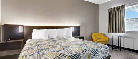 Une chambre d’hôtel moderne avec un grand lit, une table de chevet, une chaise et une fenêtre avec des rideaux.