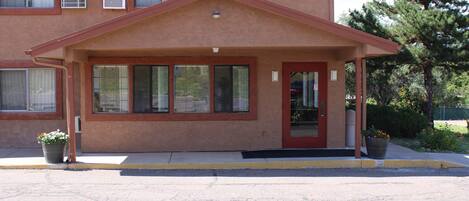 A building with a red door, large windows, and a covered entrance.