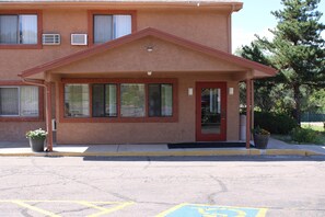 A building with a red door, large windows, and a covered entrance.