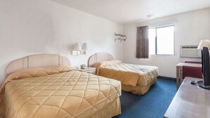 Habitació d'hotel amb dos llits, un escriptori, una televisió i una finestra amb cortines.