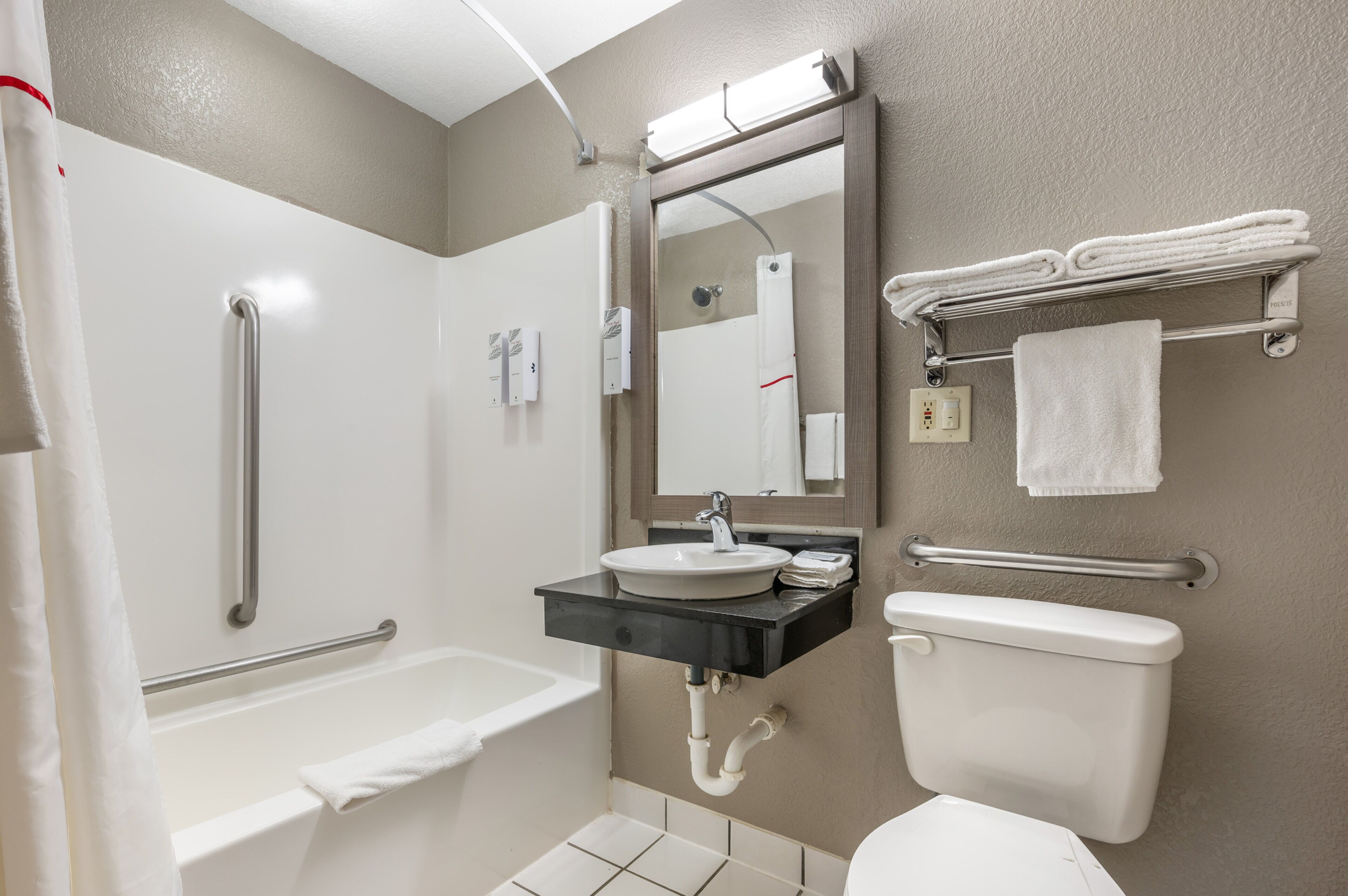 A bathroom with a bathtub, a sink, a toilet, and a shower area.
