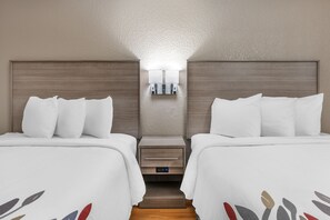 A hotel room with two beds, a nightstand with a lamp, and a small drawer unit. - Red Roof Inn Greencastle South – Cloverdale (Cloverdale)