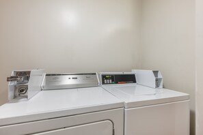 A row of white commercial washers with control panels, one of which displays a timer. - Red Roof Inn Greencastle South – Cloverdale (Cloverdale)