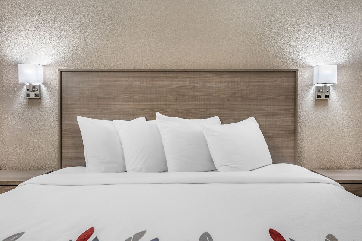 Una habitaci ón de hotel con una cama grande, dos mesitas de noche y lámparas fijadas a la pared.