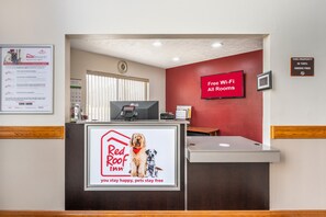 A reception desk with a Red Roof Inn sign, a Red Roof Plus sign, and a Red Roof Rewards sign. - Red Roof Inn Greencastle South – Cloverdale (Cloverdale)