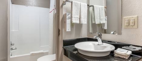 Un baño con bañera, inodoro, lavabo y espejo.