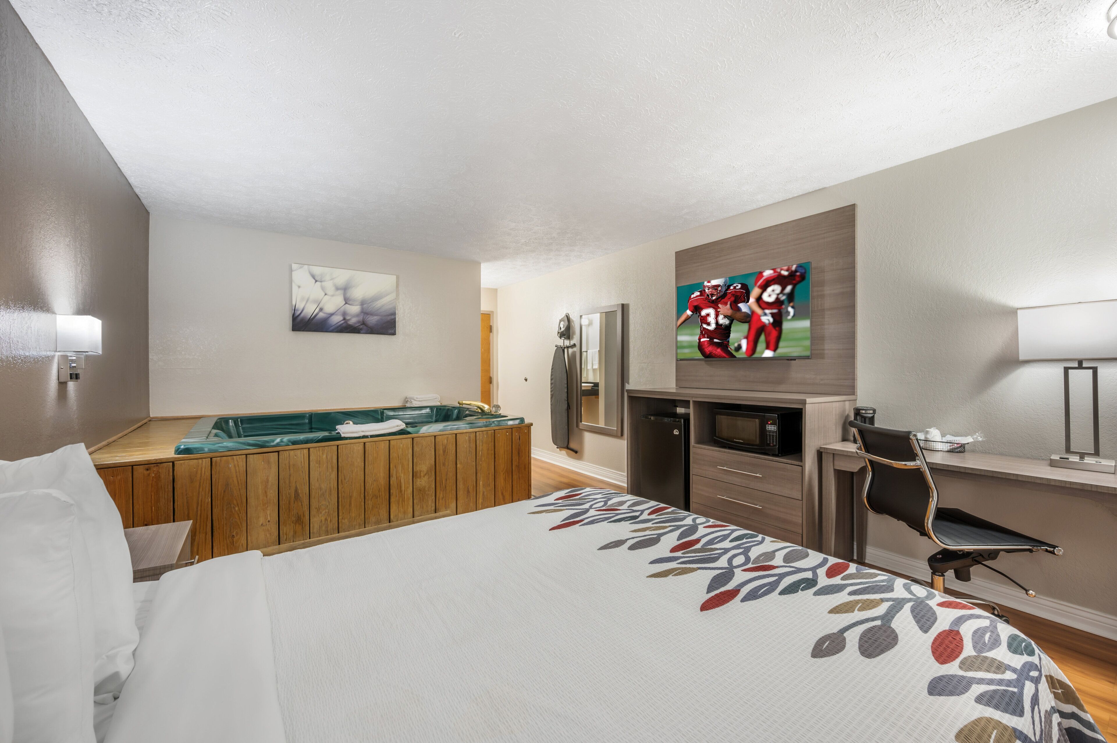 Una habitación de hotel con cama, mesa de billar, televisor, refrigerador y escritorio.