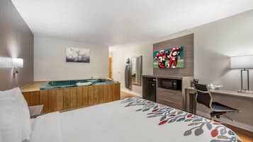 Una habitación de hotel con cama, mesa de billar, televisor, refrigerador y escritorio.
