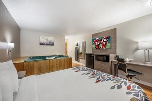 Una habitación de hotel con cama, mesa de billar, televisor, refrigerador y escritorio.