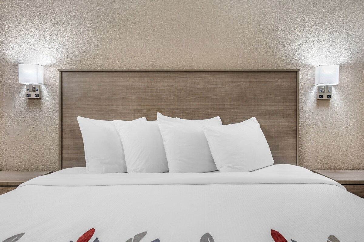 Une chambre d’hôtel avec un grand lit, deux tables de chevet et des lampes fixées au mur.