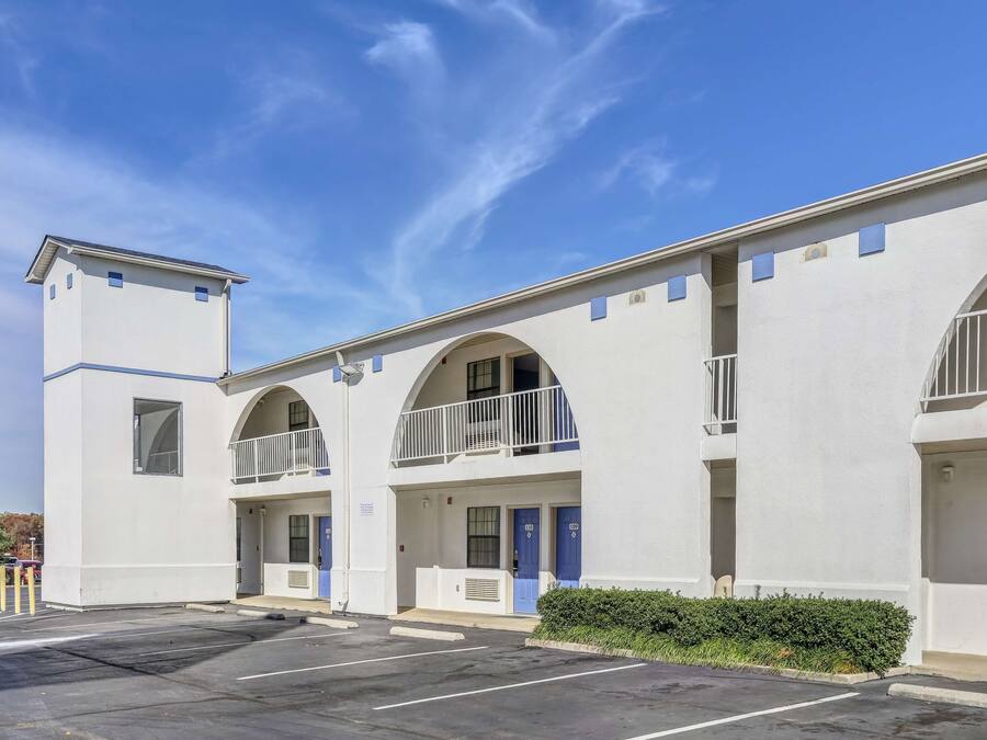 A building with a white exterior, multiple balconies, and blue doors.