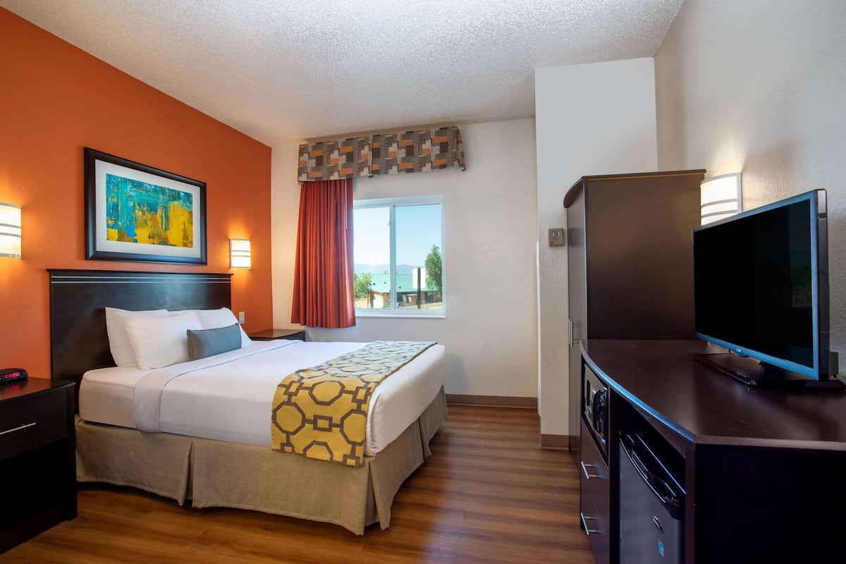 A hotel room with a bed, a television, a desk, and a window with a view.