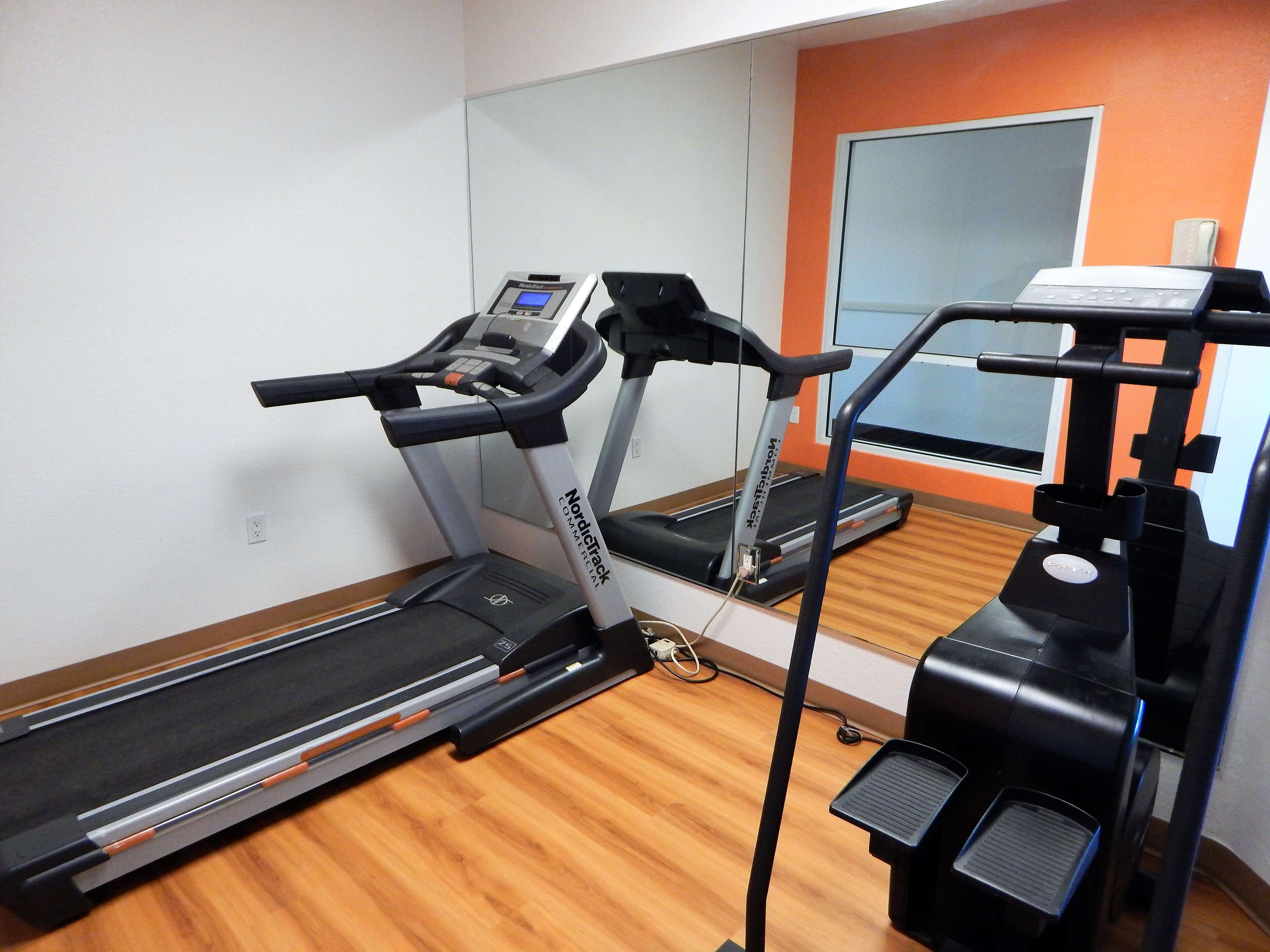 Un gimnasio con cintas de correr, escaladora y banca de pesas.