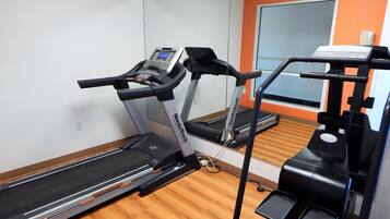 Un gimnasio con cintas de correr, escaladora y banca de pesas.