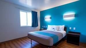 A modern hotel room with a large bed, a nightstand, a bedside table, and a window with curtains. - Motel 6 Pottstown, PA (Pottstown)
