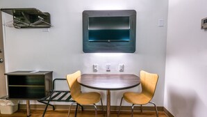 A small dining area with a table and two chairs, a wall-mounted TV, and a drying rack. - Motel 6 Pottstown, PA (Pottstown)