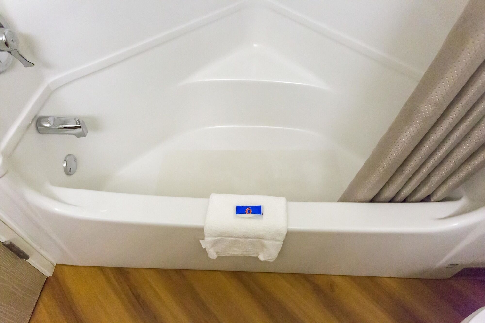A white bathtub with a shower curtain, a towel rack, and a faucet.