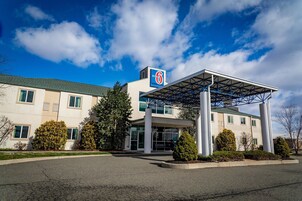 Un edificio de Motel 6 con entrada cubierta, ventanas grandes y estacionamiento.