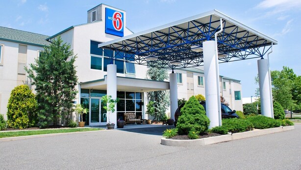 A modern motel with a prominent 'Motel 6' sign, covered parking, and a well-maintained entrance area. - Motel 6 Pottstown, PA (Pottstown)