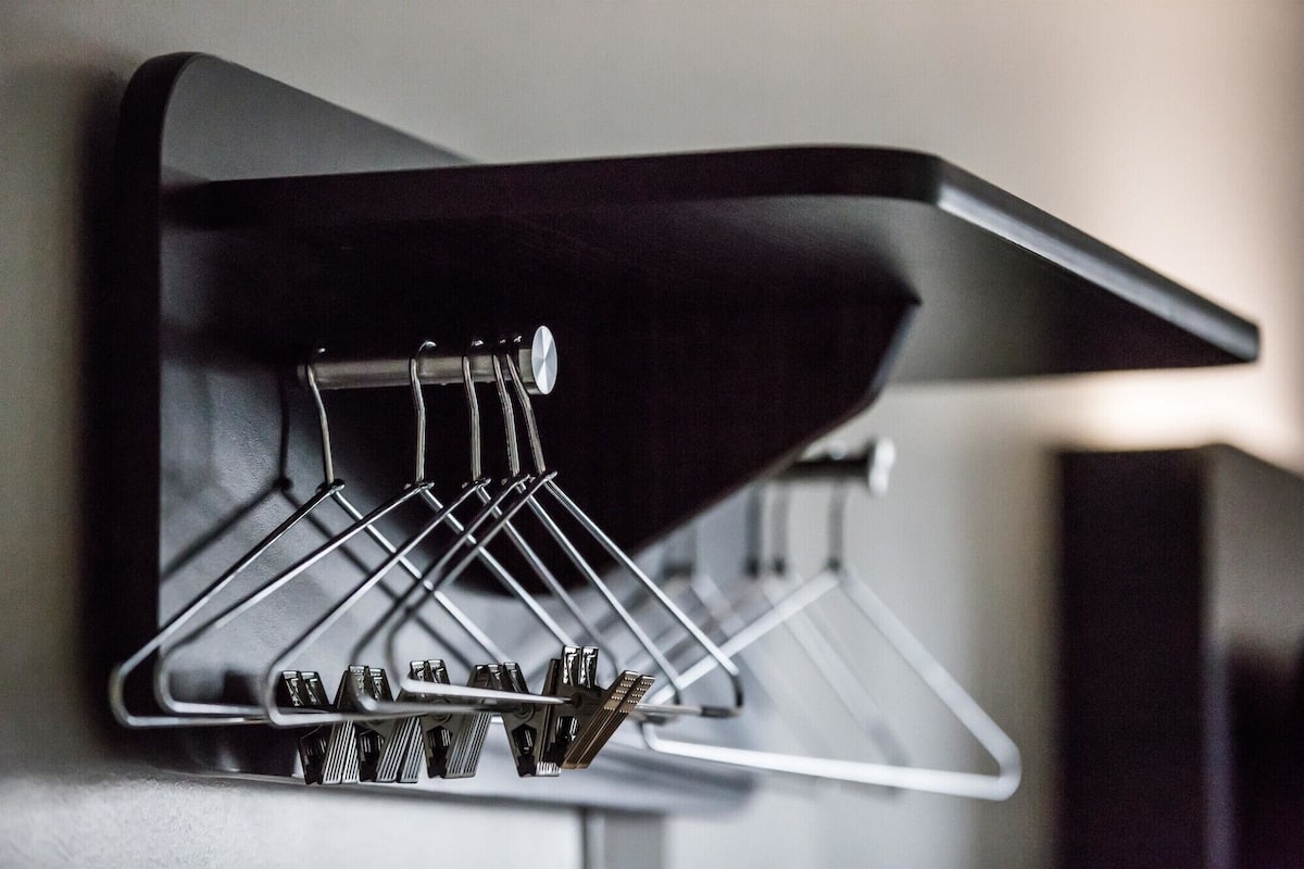A wall-mounted rack with multiple hangers and a metal hook.