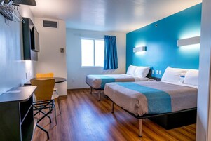 Habitación de hotel con dos camas, un escritorio y una silla.