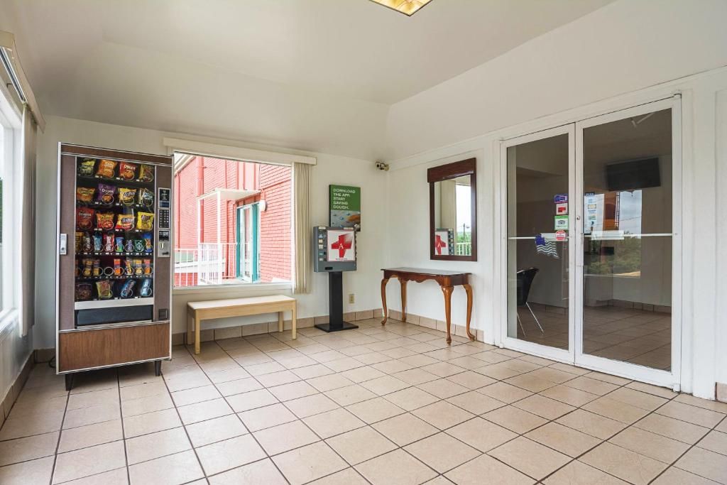 A room with a vending machine, a bench, a table, and a sliding glass door leading to an outdoor area.