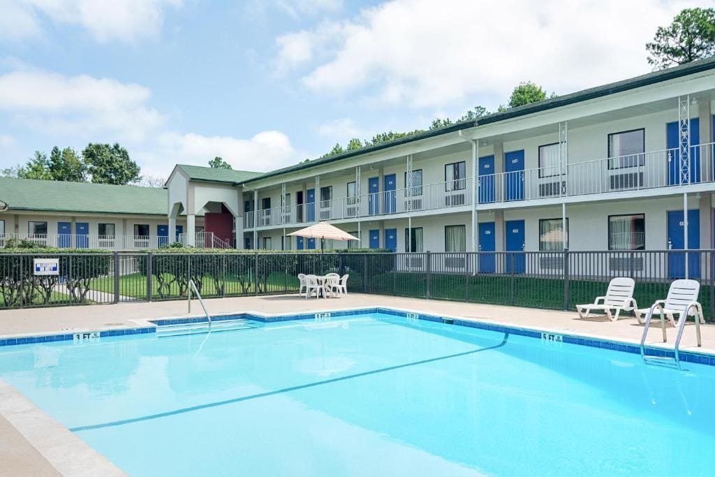 Ein Motel mit Pool, Außenbereich und einem umzäunten Bereich.