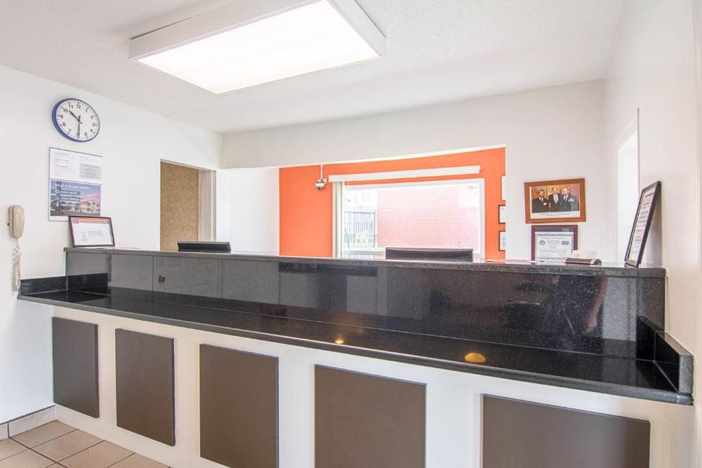A reception desk with a clock, framed certificates, and a window with blinds.