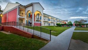 A multi-story motel with a brick facade, balconies, and a well-maintained lawn. - Motel 6 Gainesville, GA (Gainesville)