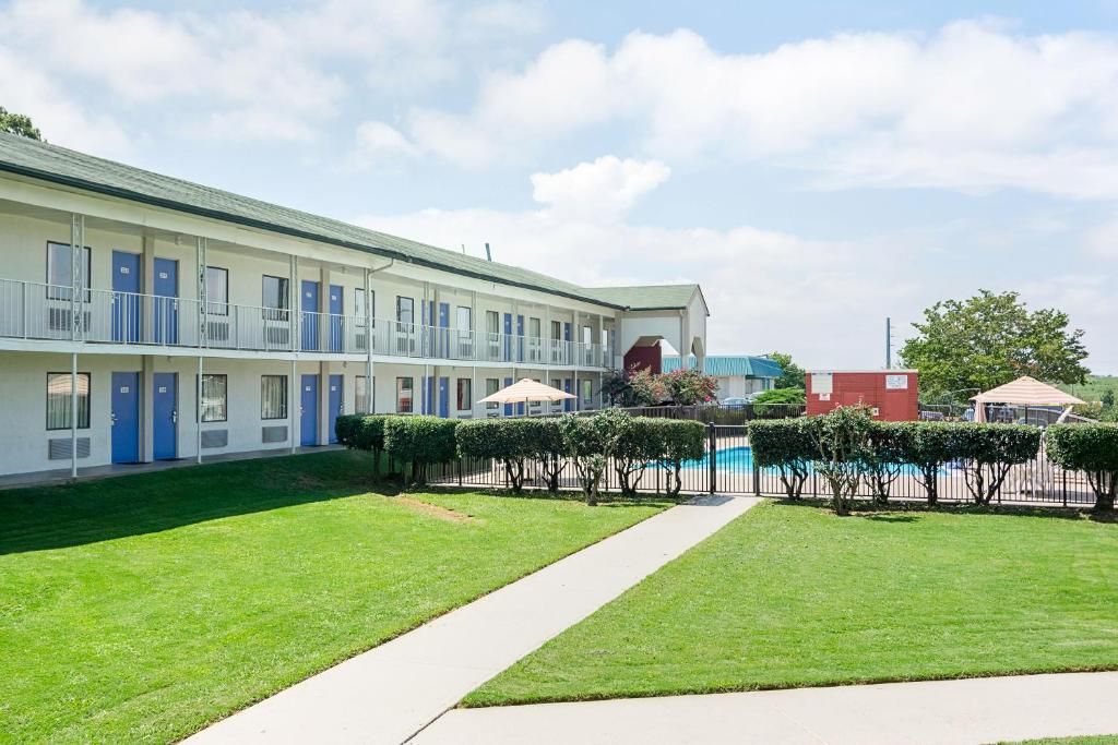 A motel with a pool, multiple rooms, and a well-maintained lawn.