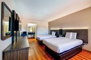 A hotel room with two beds, a wooden dresser, a mirror, and a bathroom visible through an open door. - Motel 6 Gainesville, GA (Gainesville)