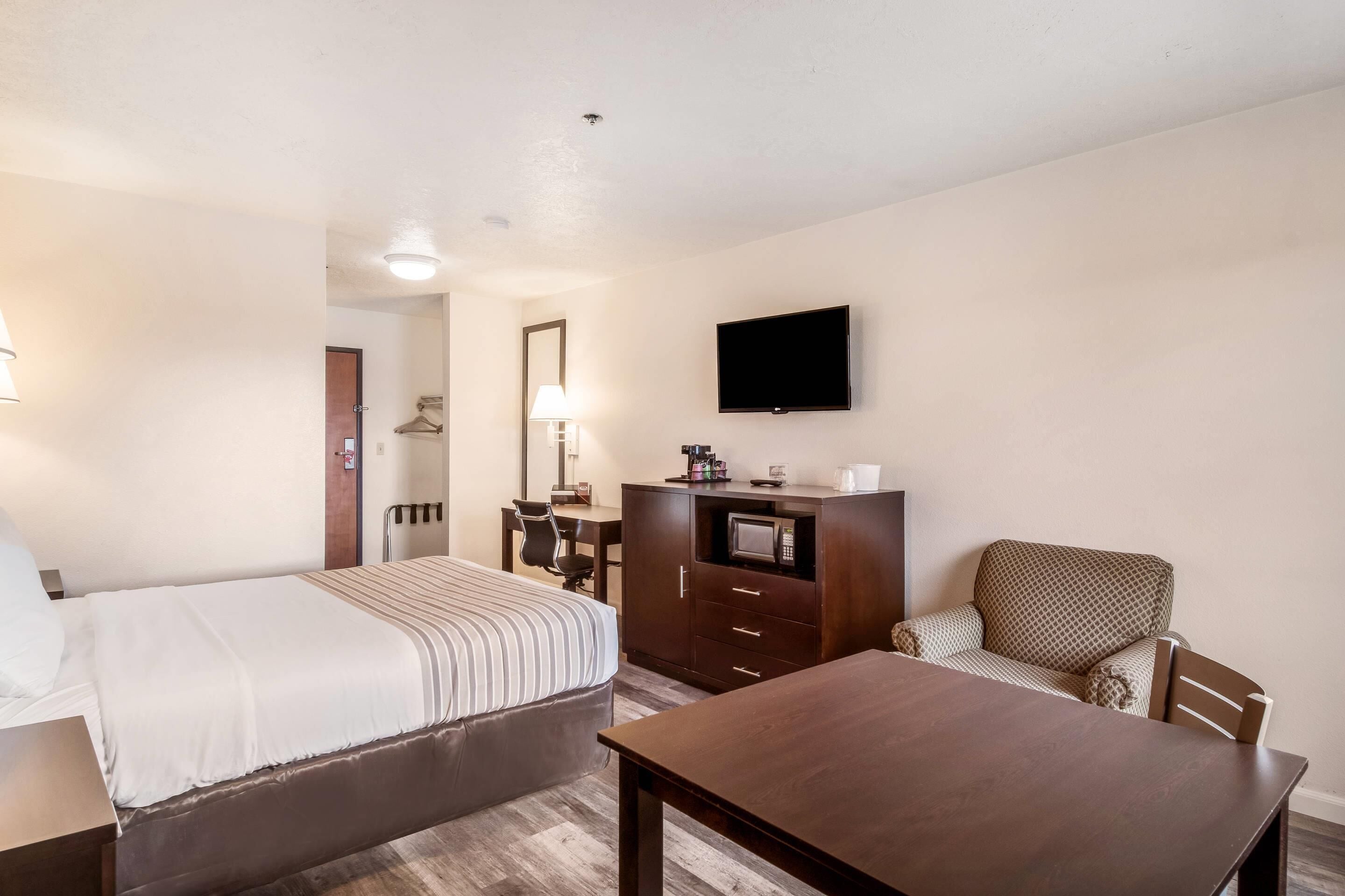 Une chambre d’hôtel équipée d’un lit, d’un bureau, d’une chaise, d’une télévision et d’un four à micro-ondes.