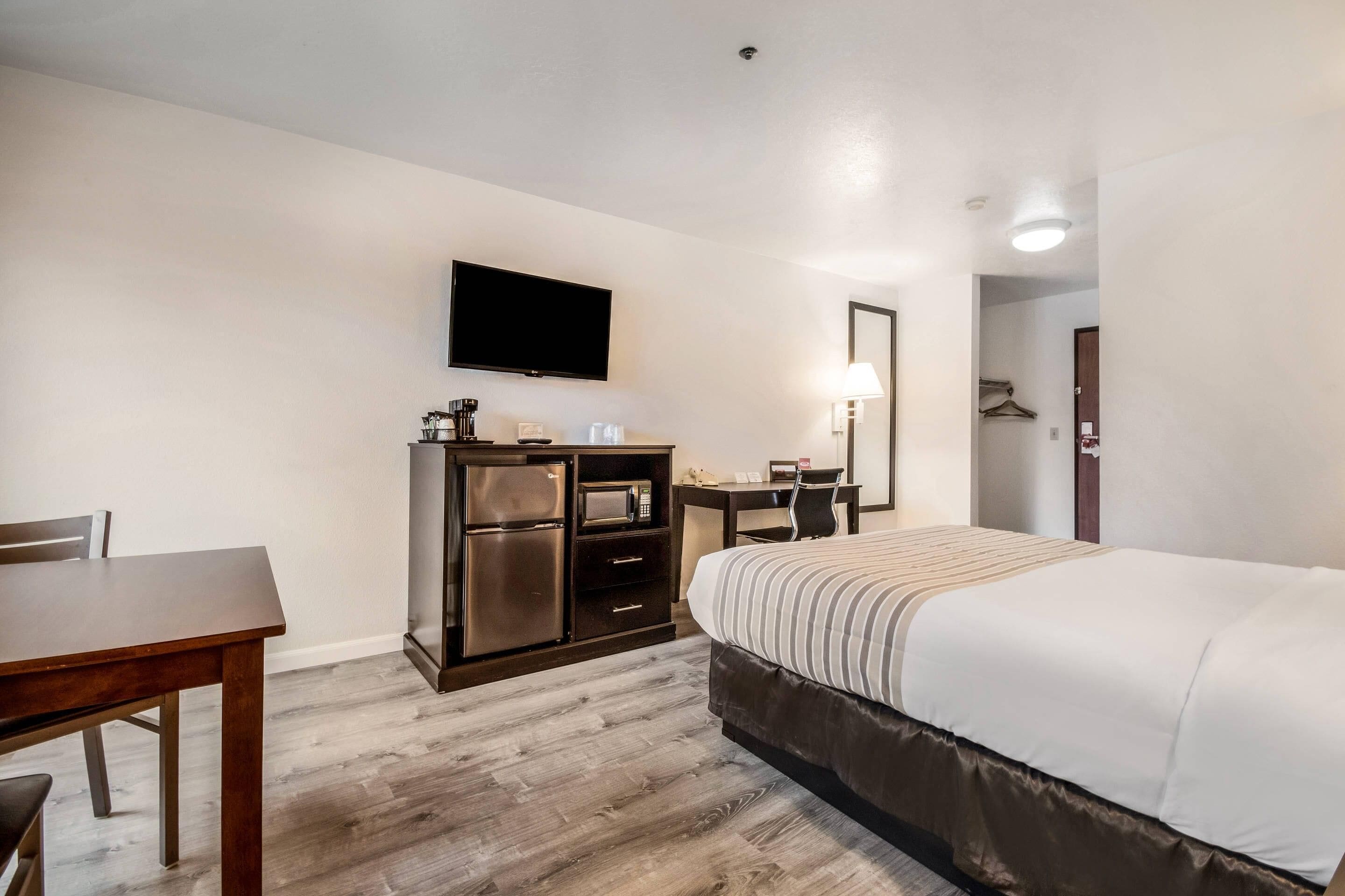 Une chambre d’hôtel équipée d’un lit, d’un bureau, d’une télévision, d’un four à micro-ondes et d’une armoire.