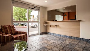 Zona de recepción con un sofá, una puerta de vidrio que da al exterior y un mostrador de recepción.